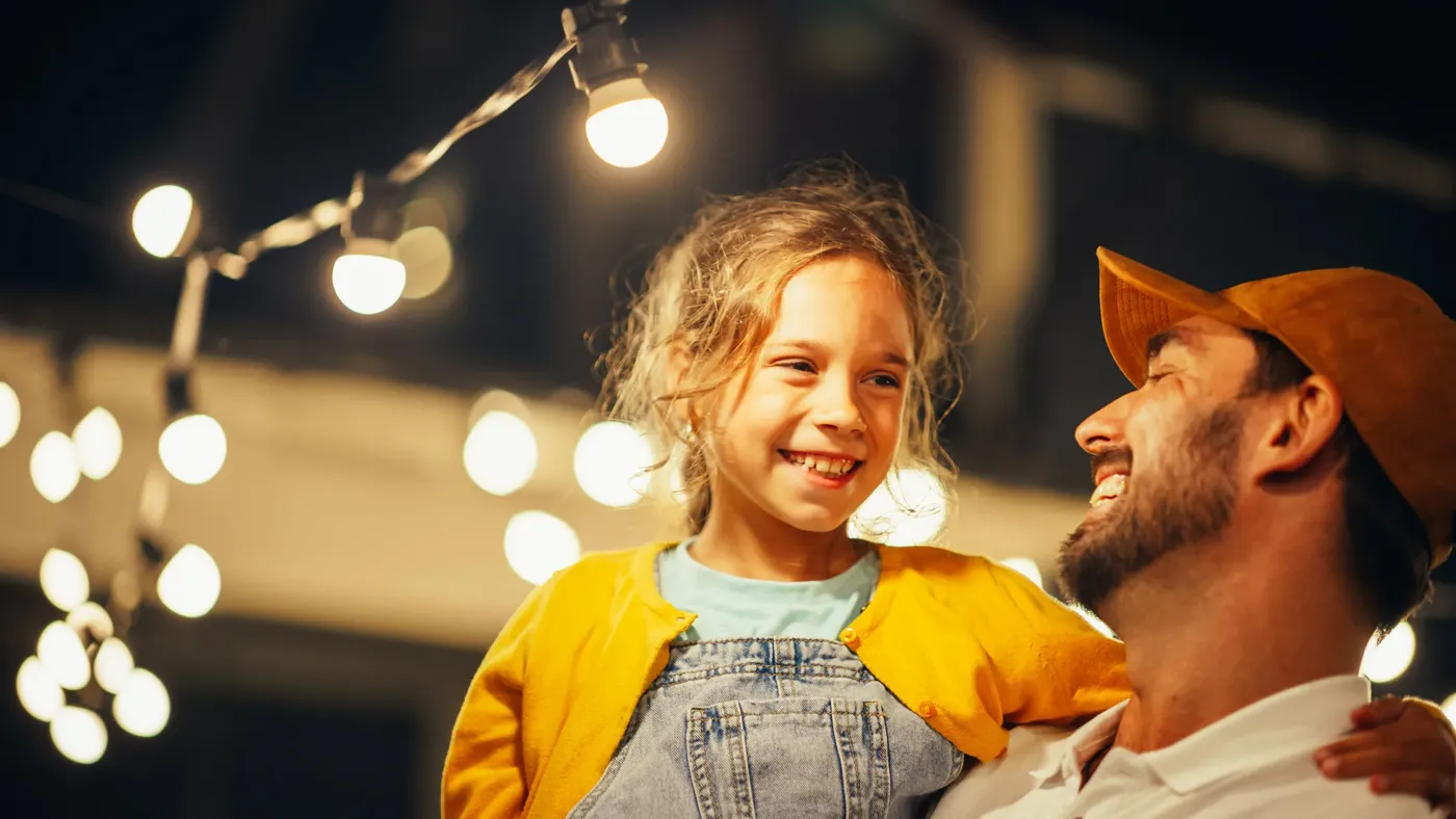 Smiling child and parent under string lights